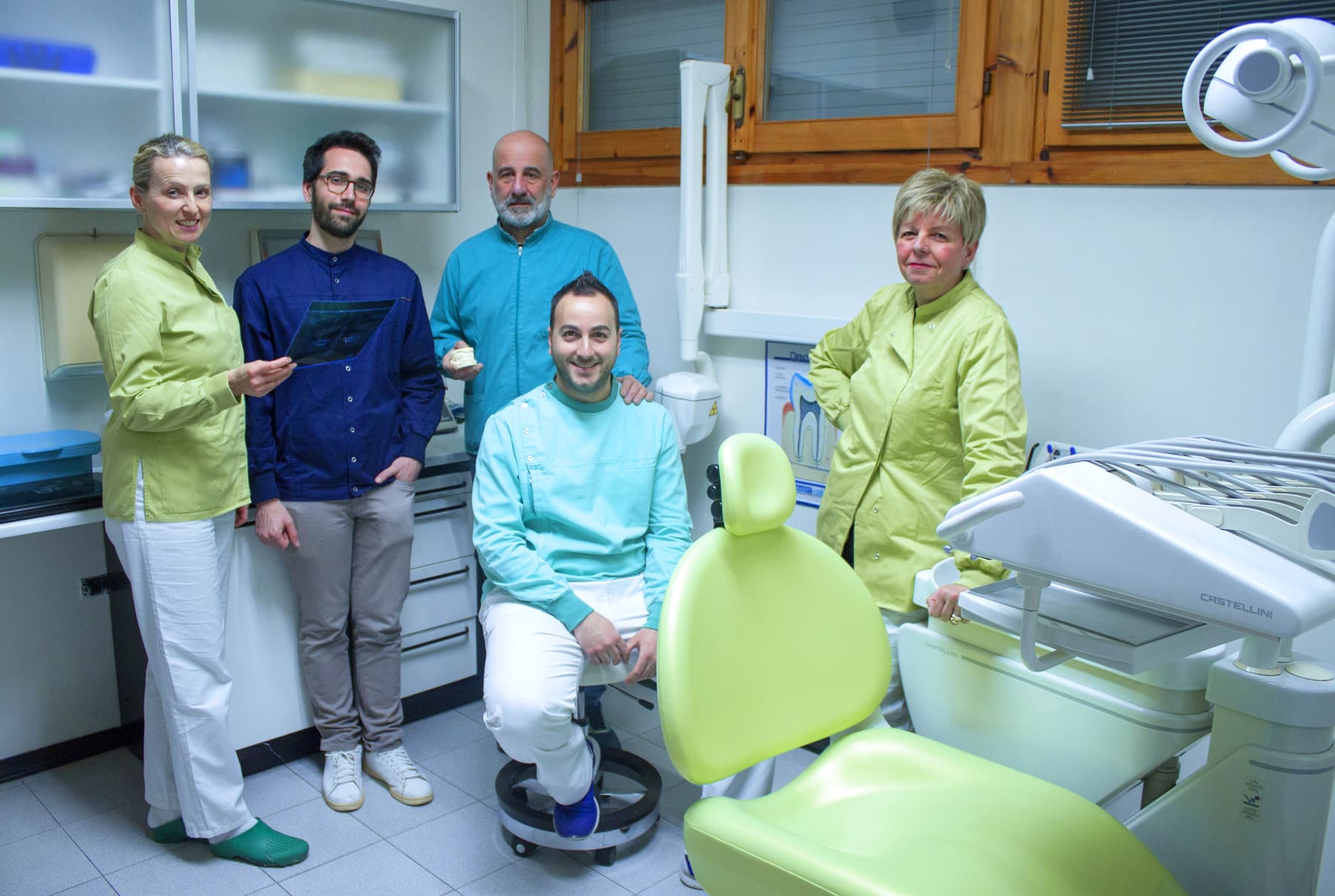 Il team dello studio attorno alla poltrona verde, nella sala di cura